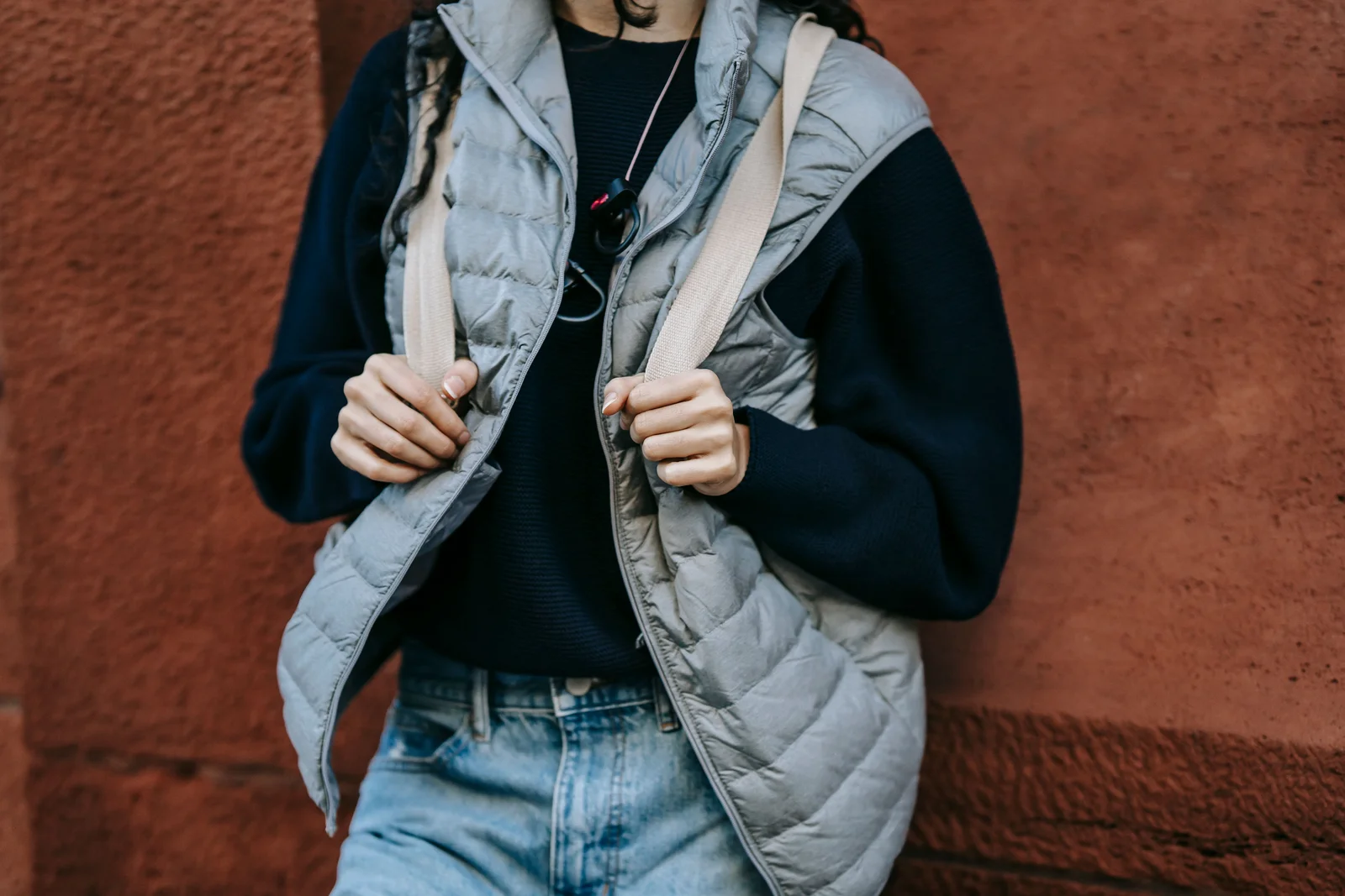 Femme en gilet sans manche matelassé par-dessus un haut à manches longues et un jean