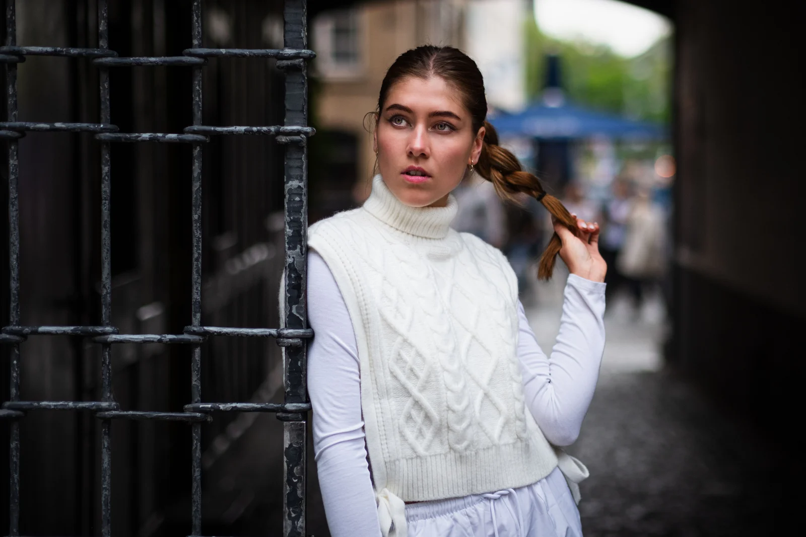 Femme portant un gilet sans manche en maille par-dessus un col roulé fin blanc