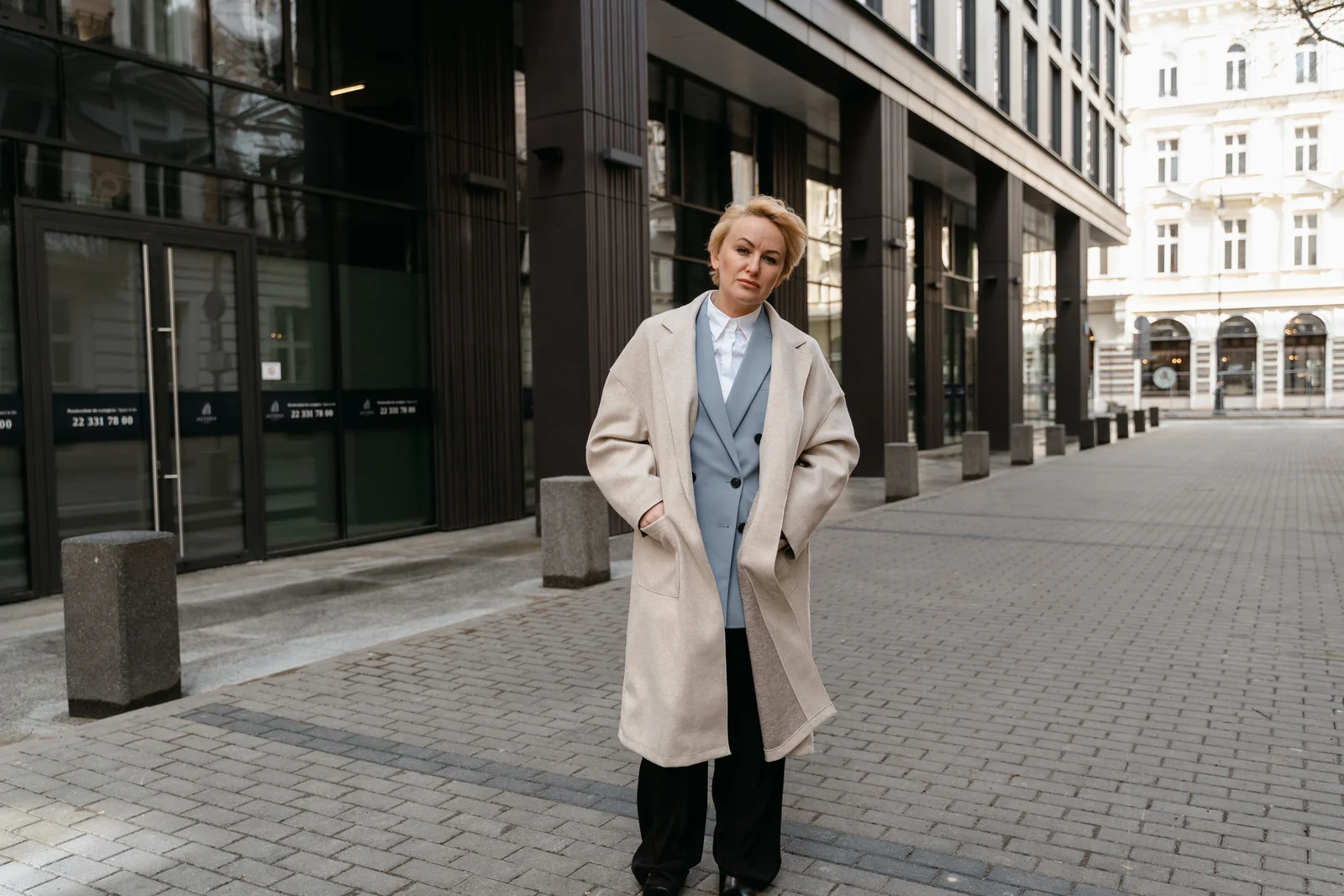 Silhouette féminine en manteau beige et pantalon noir dans la rue
